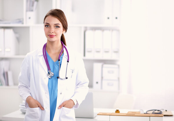 Portrait of young woman doctor with white coat standing in hospital