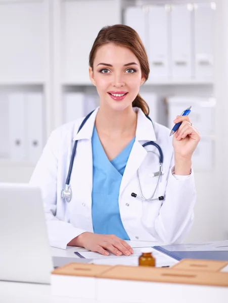 Female doctor sitting on the desk and working a laptop in hospital — Stock Photo, Image