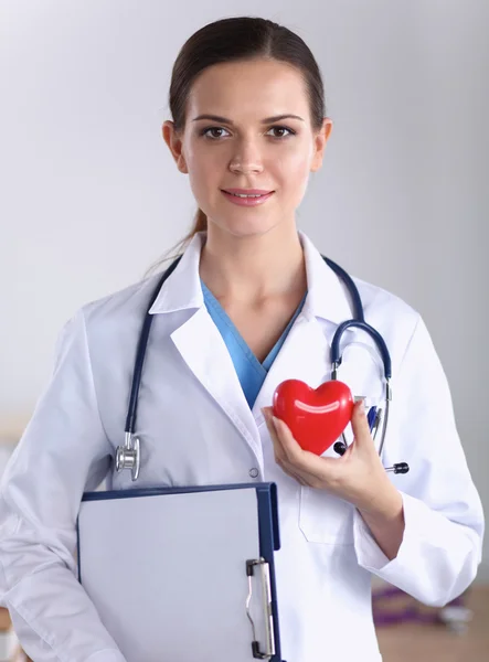 Dosyası olan genç bir kadın doktor ve beyaz arka planda izole edilmiş kırmızı bir kalp. — Stok fotoğraf