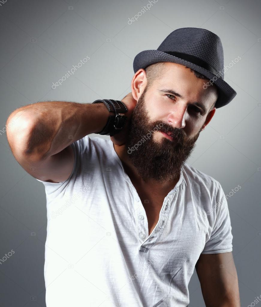 Portrait of handsome bearded man in hat standing , isolated on grey background