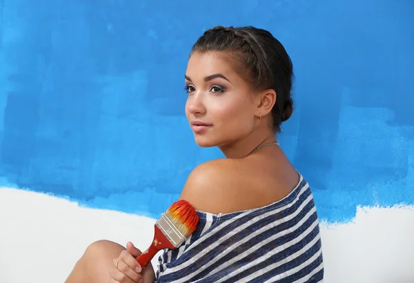 Portret van vrouwelijke schilder zittend op de vloer in de buurt van muur naar schilderij. — Stockfoto