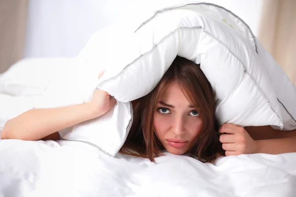 Mujer acostada en la cama y cerrando las orejas con almohada — Foto de Stock