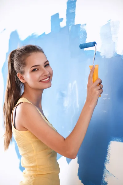 Feliz bela jovem fazendo pintura de parede, de pé na escada — Fotografia de Stock