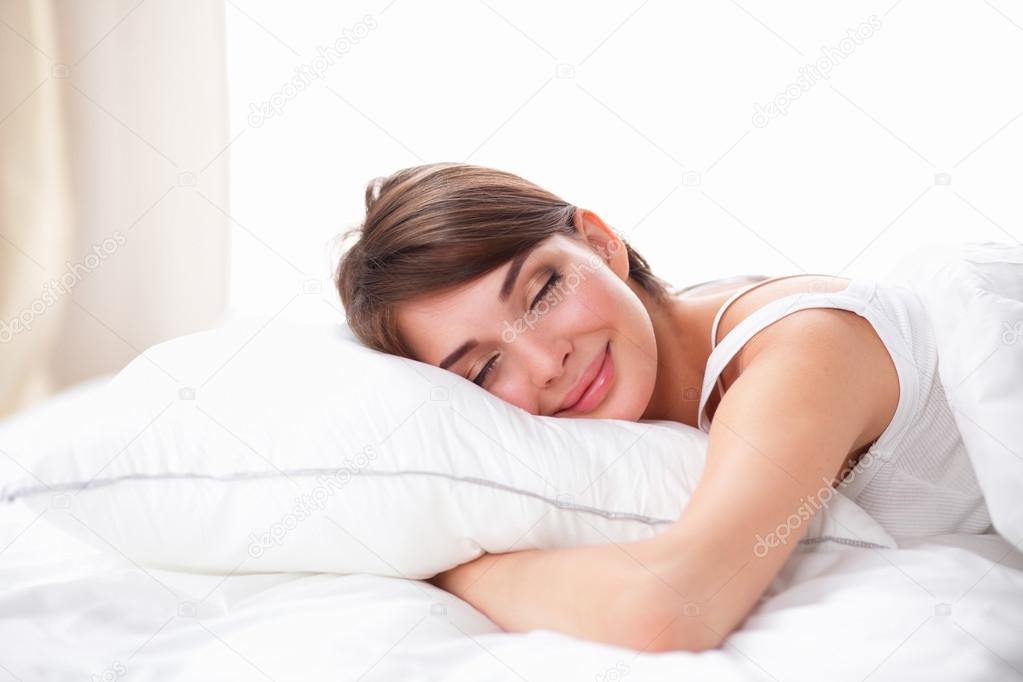Beautiful girl sleeps in the bedroom, lying on bed