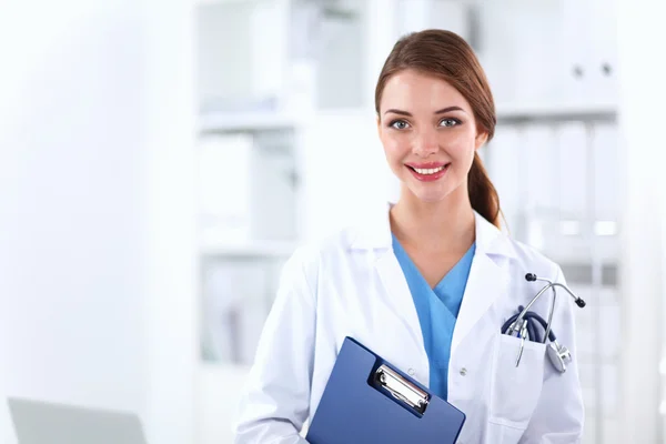 Médico sonriente con una carpeta en uniforme de pie en el hospital —  Fotos de Stock