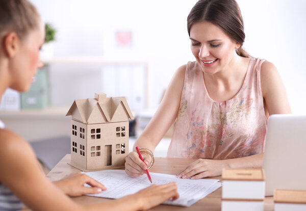 Portrait of female architect with blueprints at desk in office