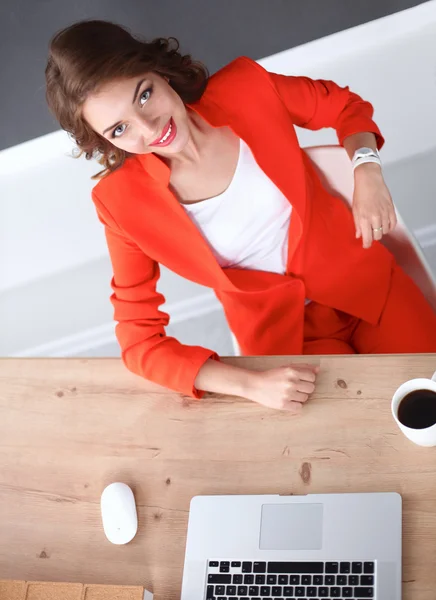 Atraktivní žena sedící za stolem v kanceláři, pracující s notebookem — Stock fotografie