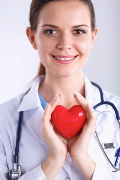 Mujer joven doctora sosteniendo un corazón rojo, aislado sobre fondo blanco —  Fotos de Stock