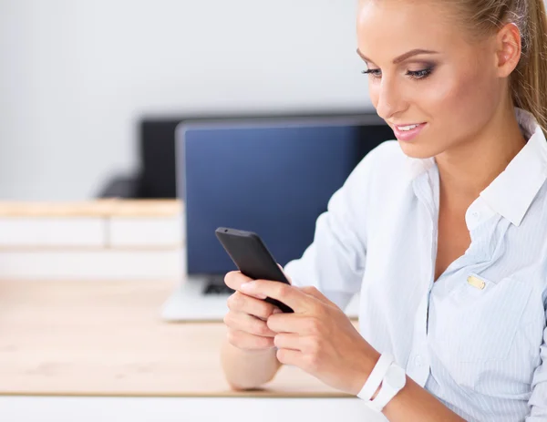 Businesswoman sending message with smartphone sitting in the office — Stock Photo, Image