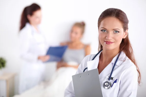 Médico sonriente con una carpeta en uniforme de pie en el hospital — Foto de Stock