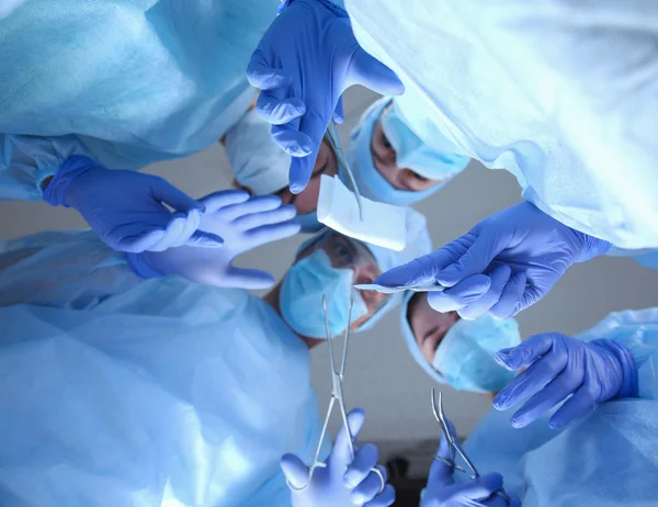 Cirujanos sosteniendo instrumentos médicos en las manos y mirando al paciente — Foto de Stock