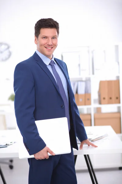 Zakenman of manager die op kantoor tegen zijn bureau staat — Stockfoto