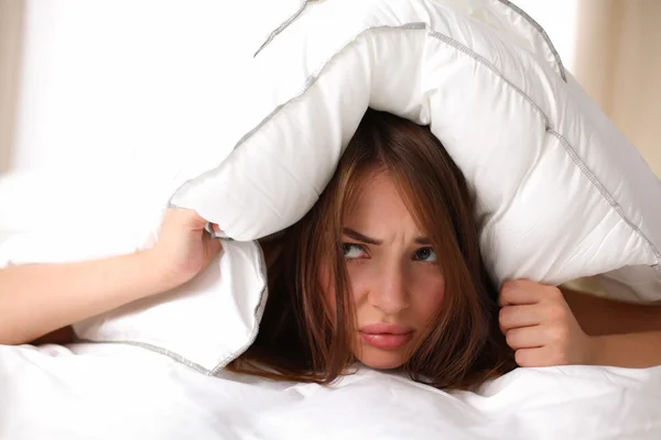 Mujer acostada en la cama y cerrando las orejas con almohada —  Fotos de Stock