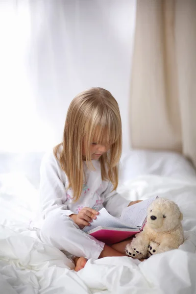 Niña acostada en la cama y leyendo un libro —  Fotos de Stock