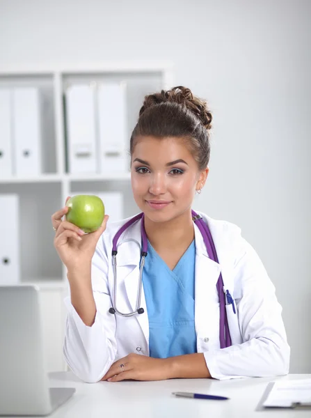 Kadın doktor, elinde yeşil bir elma, oturuyor. — Stok fotoğraf