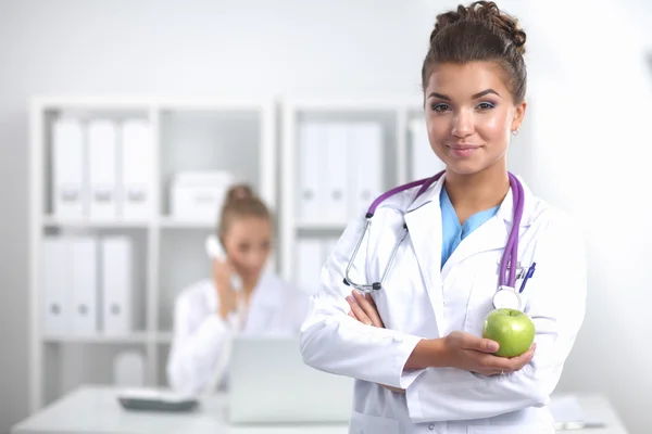 Female doctor hand holding a green apple, standing — Stock Photo, Image