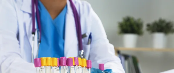 Woman researcher is surrounded by medical vials and flasks, isolated on white background — Stock Photo, Image