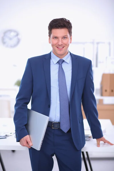 Zakenman of manager die op kantoor tegen zijn bureau staat — Stockfoto