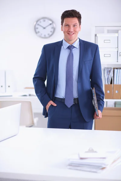 Zakenman of manager die op kantoor tegen zijn bureau staat — Stockfoto