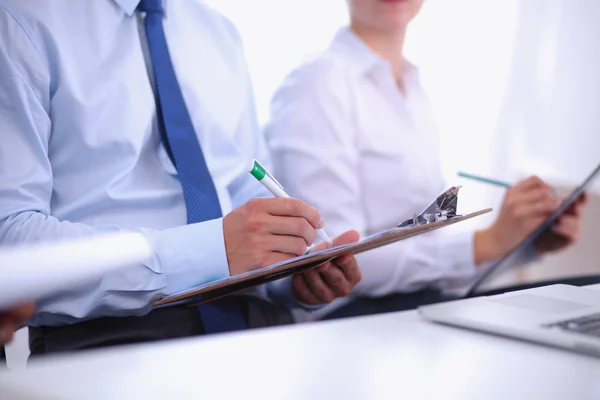 Zakenmensen zitten en schrijven op zakelijke bijeenkomst, in functie — Stockfoto