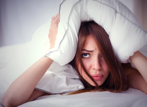 Mujer acostada en la cama y cerrando las orejas con almohada — Foto de Stock