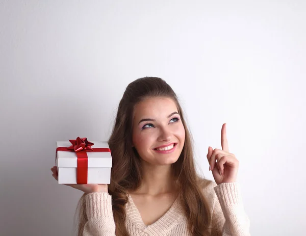 Mujer joven sonrisa feliz celebrar caja de regalo en las manos, de pie sobre fondo gris —  Fotos de Stock