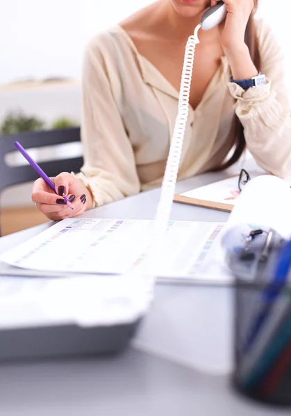 Jeune femme d'affaires assise au bureau et parlant au téléphone — Photo