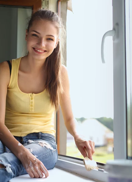 Vrouw schilderij muur van een appartement met een penseel zorgvuldig afwerking af rond raamkozijn — Stockfoto