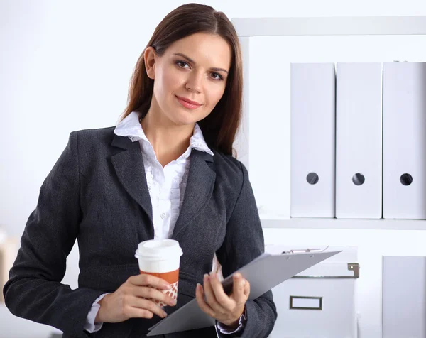 Atractiv tânără femeie de afaceri în picioare lângă birou cu dosar în birou — Fotografie, imagine de stoc