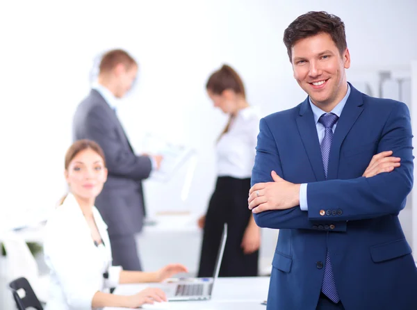 Succesvolle business man die met zijn personeel in de achtergrond op kantoor — Stockfoto