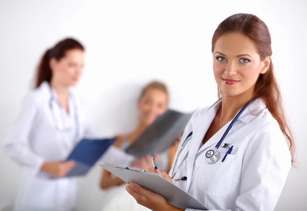 Médico sonriente con una carpeta en uniforme de pie en el hospital — Foto de Stock