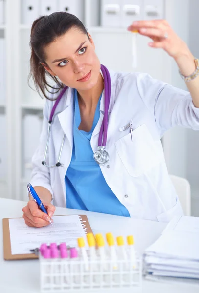 Kvinnlig forskare är omgiven av medicinska flaskor och kolvar, isolerade på vit bakgrund — Stockfoto