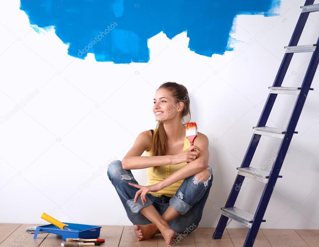 Portrait of female painter sitting on floor near wall after painting.