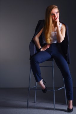 Genç bir kadın sandalyede oturuyor.