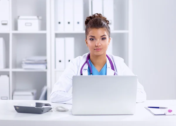 Vrouwelijke arts zit op het bureau en werkt een laptop in het ziekenhuis — Stockfoto