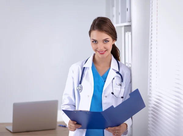 Sorridente medico donna con una cartella in uniforme in piedi in ospedale — Foto Stock