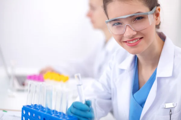 Woman researcher is surrounded by medical vials and flasks, isolated on white background — Stock Photo, Image