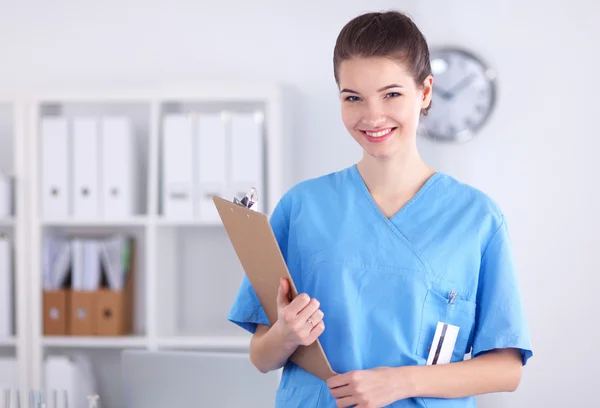 Médico sonriente con una carpeta en uniforme de pie en el hospital —  Fotos de Stock