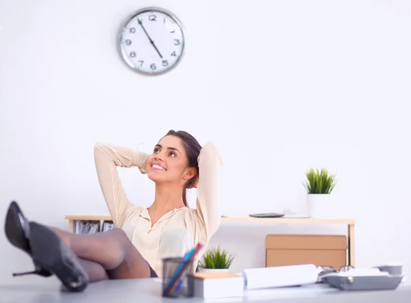 Geschäftsfrau entspannt sich mit den Händen hinter dem Kopf und sitzt auf einem Bürostuhl — Stockfoto