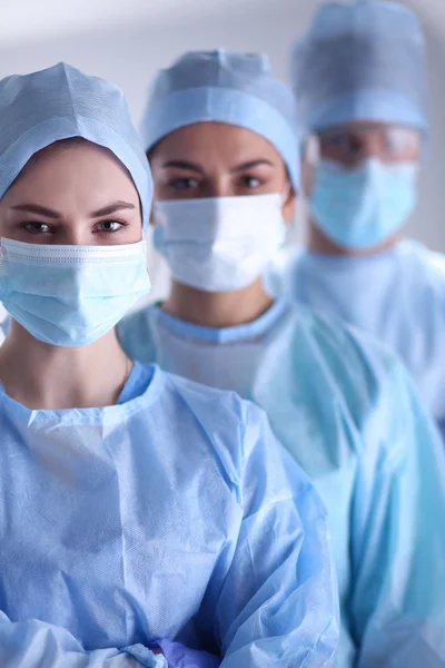 Equipo de cirujanos, con uniformes de protección, gorras y máscaras — Foto de Stock