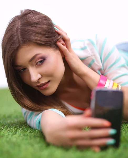 Bella giovane donna che fa selfie dal suo telefono mentre si trova in erba verde — Foto Stock