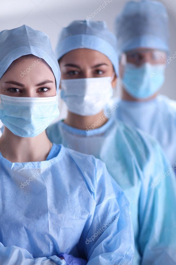 Surgeons team, wearing protective uniforms,caps and masks Stock Photo