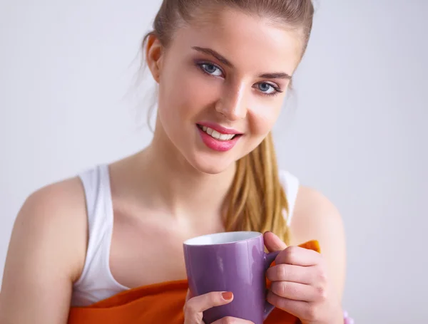 Mujer joven sentada con almohada y sosteniendo una taza de té —  Fotos de Stock