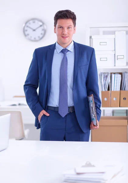 Zakenman of manager die op kantoor tegen zijn bureau staat — Stockfoto