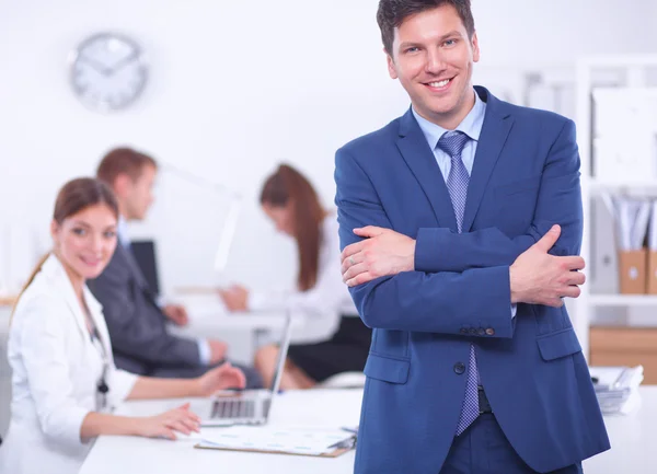 Successful business man standing with his staff in background at office — Stock Photo, Image