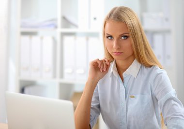 Ofiste dizüstü bilgisayarı olan çekici bir iş kadını.