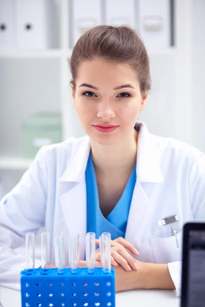 Woman researcher is surrounded by medical vials and flasks, isolated on white background — Stock Photo, Image