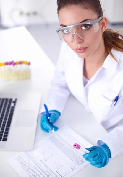 Woman researcher is surrounded by medical vials and flasks, isolated on white background — Stock Photo, Image