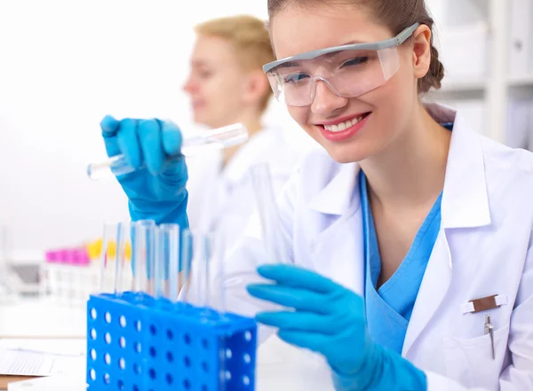 Woman researcher is surrounded by medical vials and flasks, isolated on white background — Stock Photo, Image