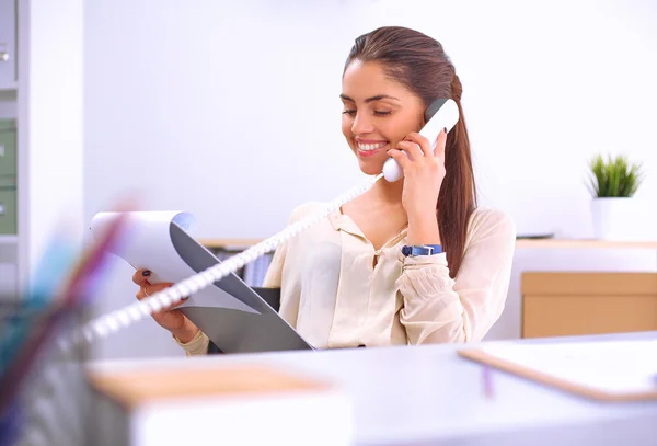 Joven mujer de negocios sentada en el escritorio y hablando por teléfono — Foto de Stock